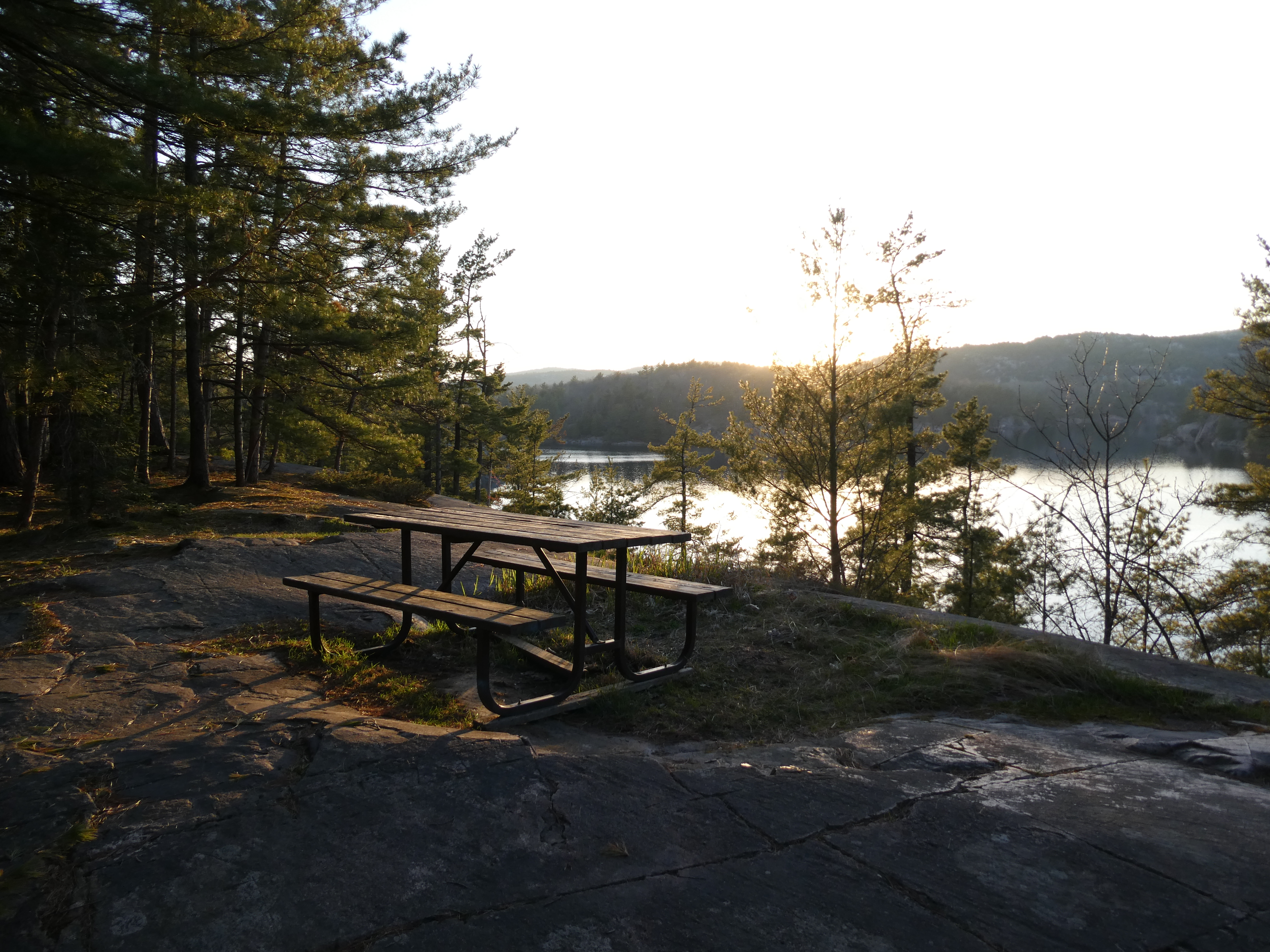 a picnic bench on a cliff over a lake